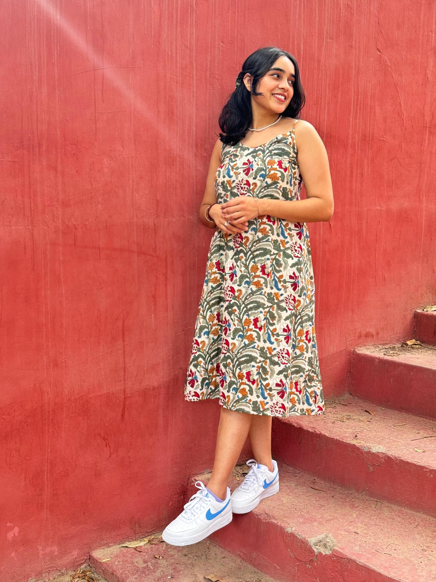 A woman standing on a set of stairs, wearing a floral hand block printed summer dress.