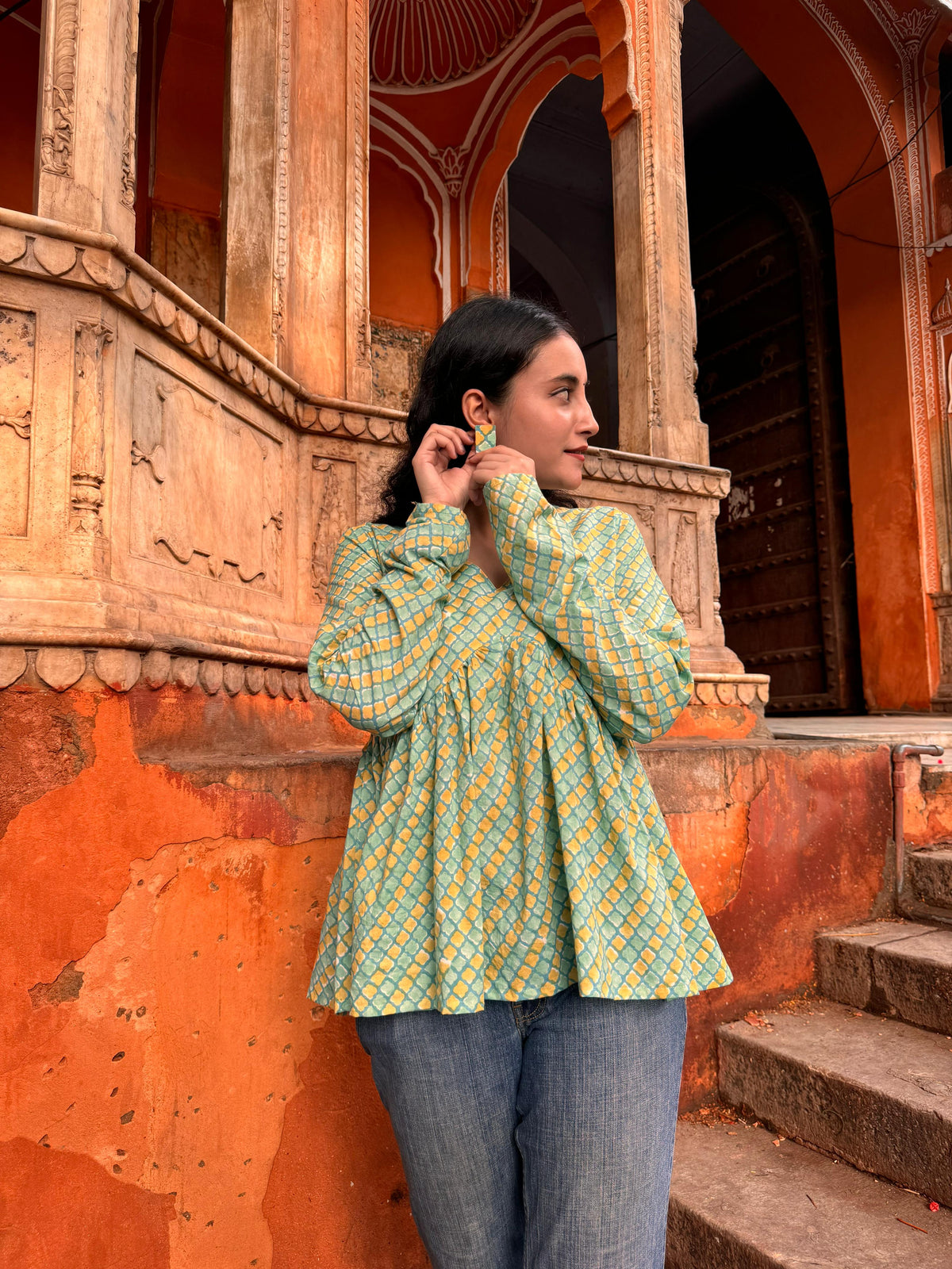 A woman wearing a yellow or green floral cotton peplum top