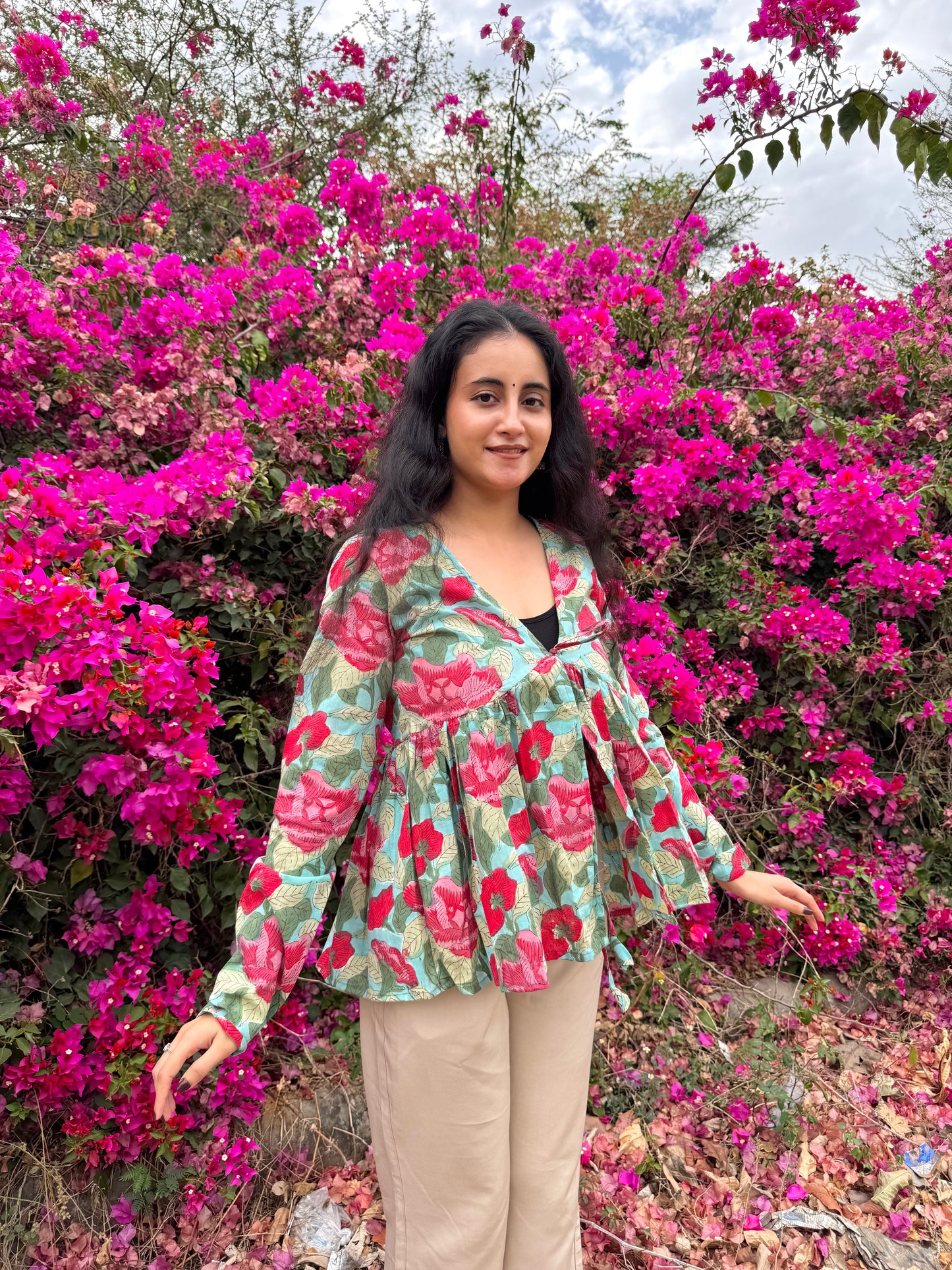 Woman standing in front of a vibrant pink flowering bush