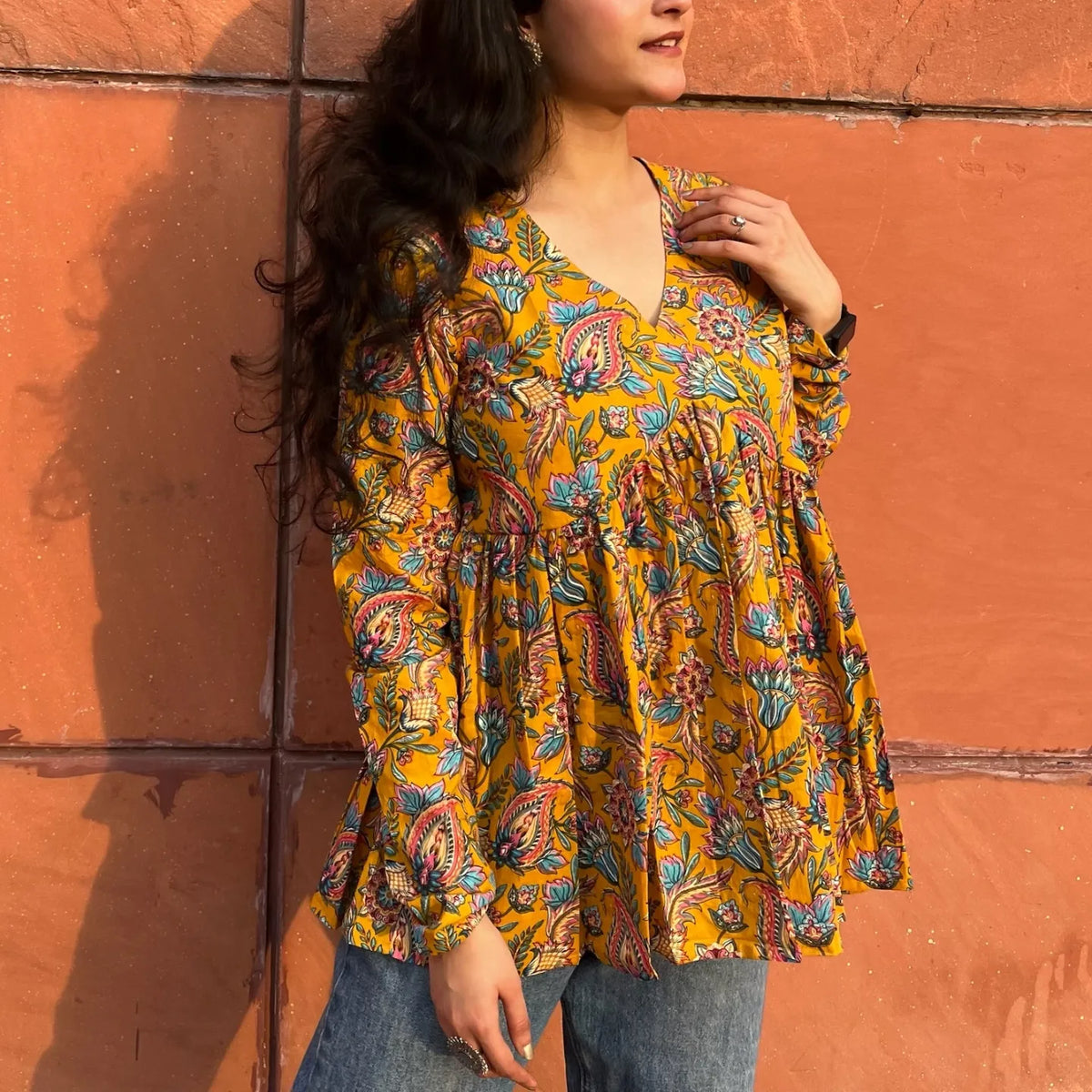 A woman wearing a yellow printed floral cotton top