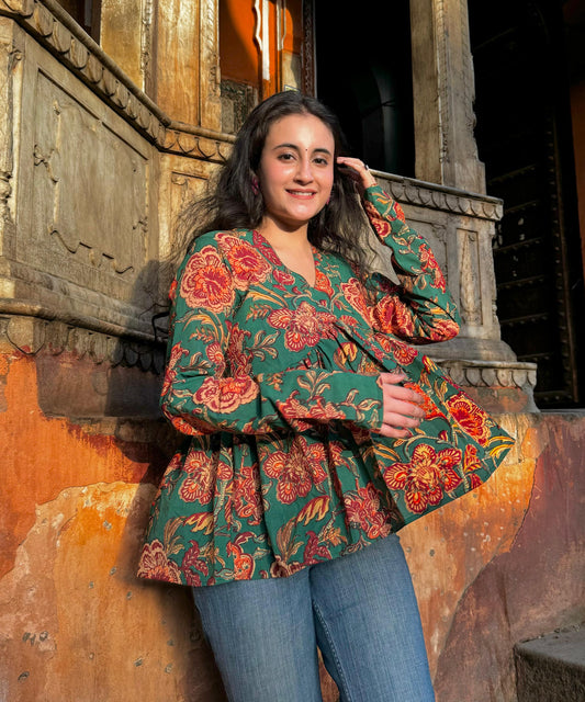 A woman wearing a green kurta with floral print, posing against an orange wall