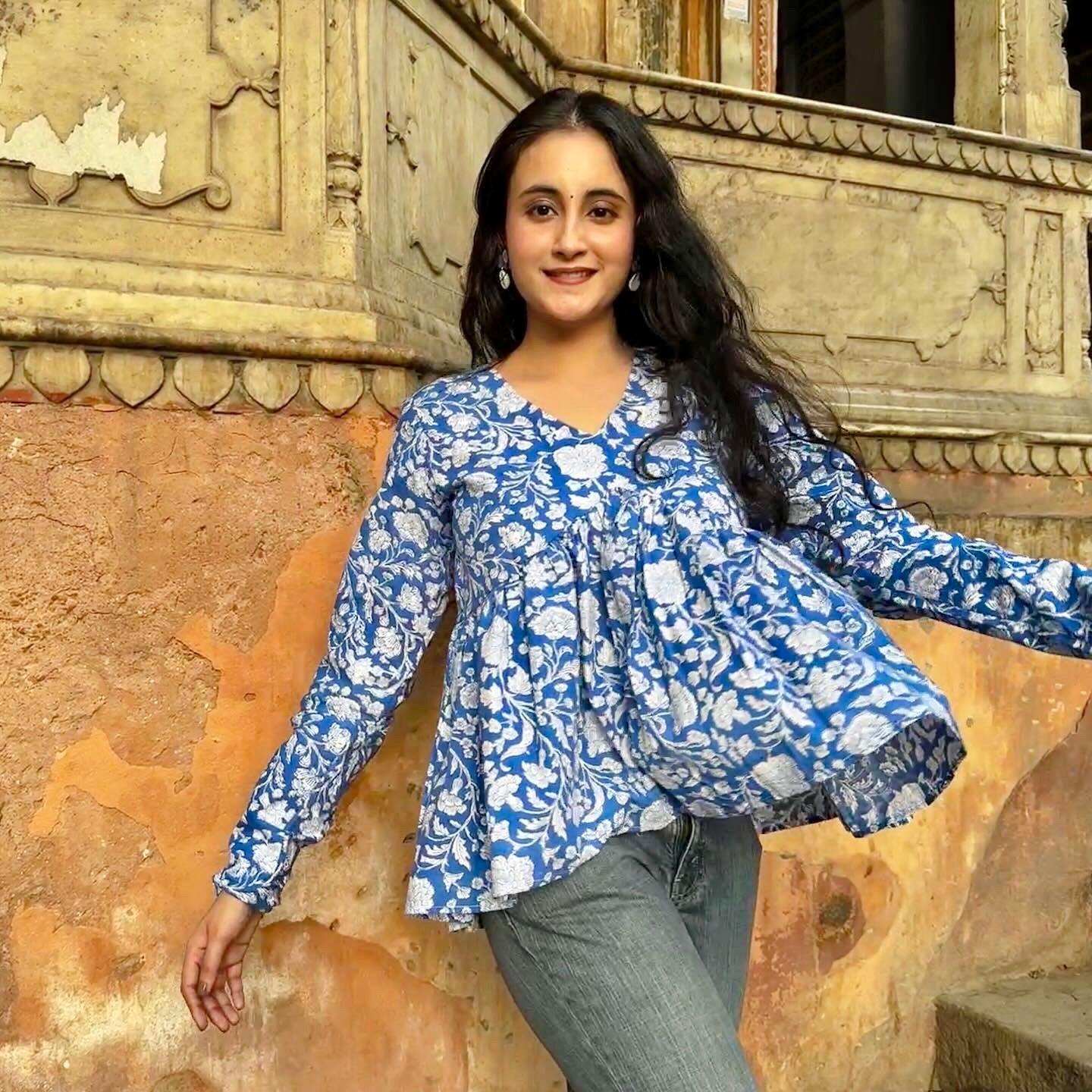 A woman wearing a blue and white hand-block printed, 100% cotton kurti, standing in front of an old building.