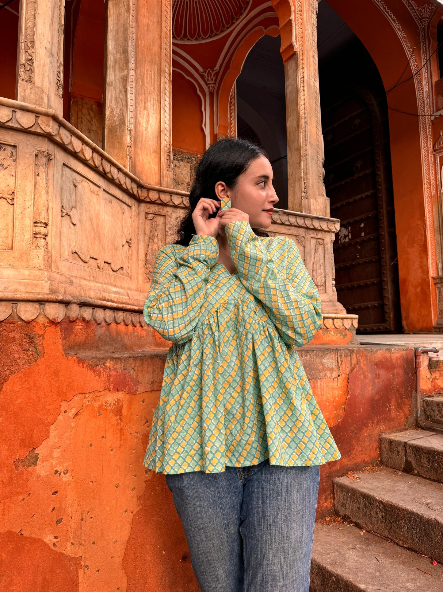  A woman wearing a yellow or green floral cotton peplum top