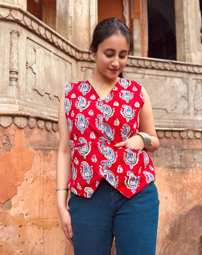 A woman wearing a red and blue geometric patterned vest top with a round neckline, paired with blue jeans.