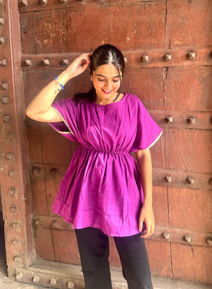 Woman wearing a purple dress standing in front of a wooden door.