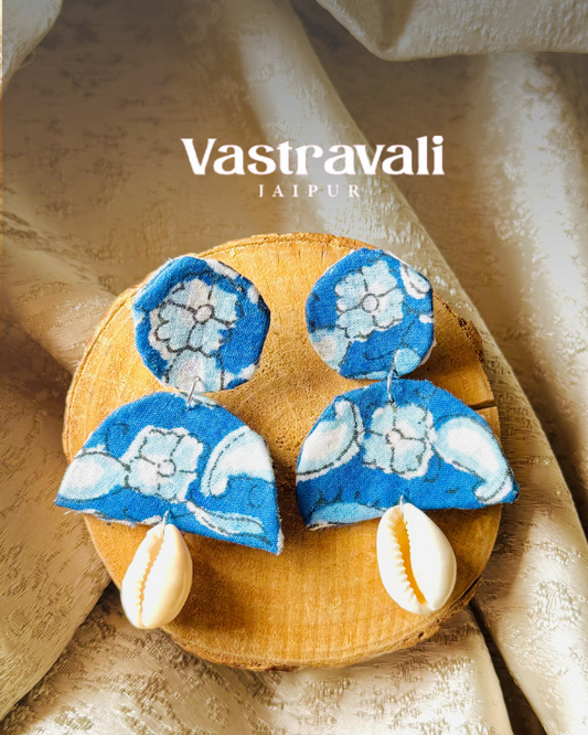 Blue floral earrings on a wooden plate with 'Vastravali' branding.