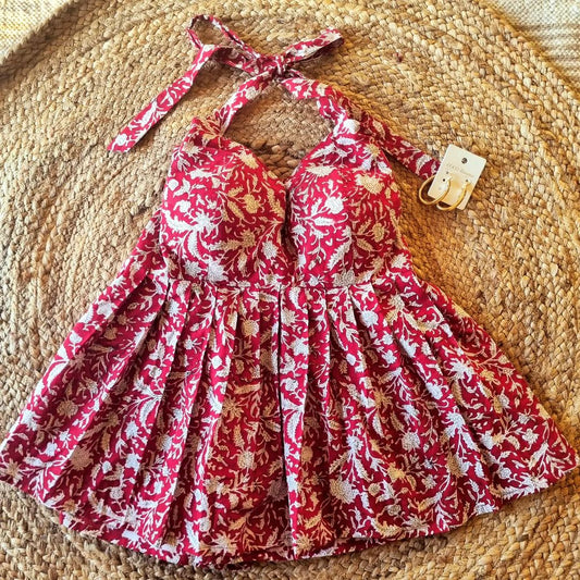 A red halter neck top with a floral pattern, displayed on a woven surface.