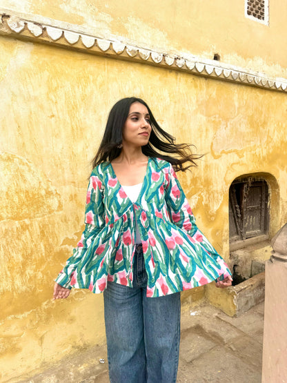 Woman wearing a colorful floral blouse against a yellow wall.