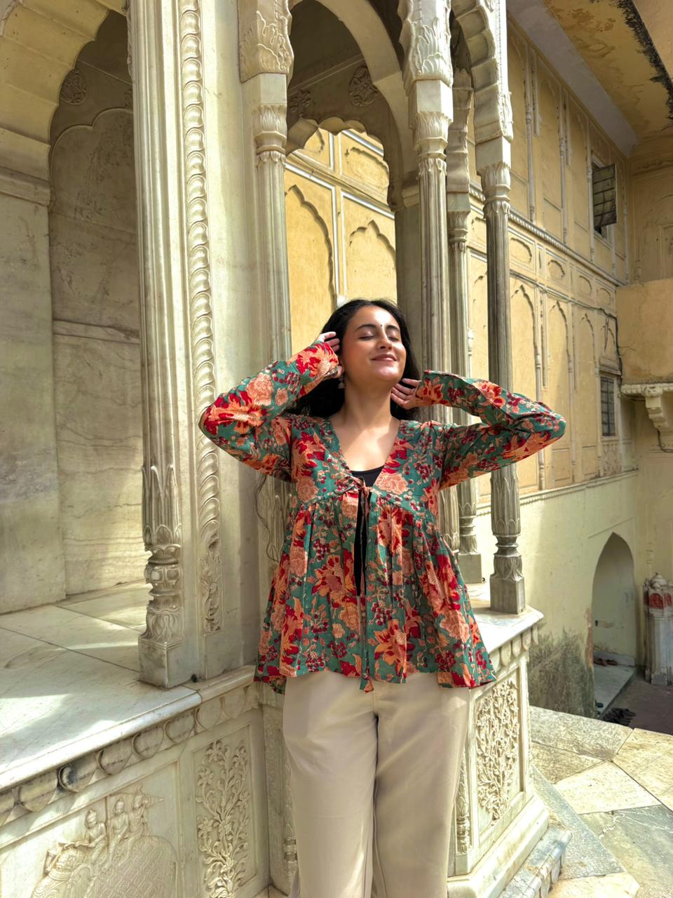 Woman in a floral blouse standing in an ornate architectural setting