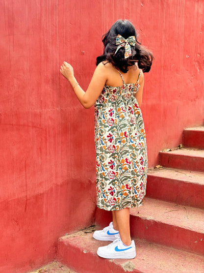 A woman standing on a set of stairs, wearing a floral hand block printed summer dress.
