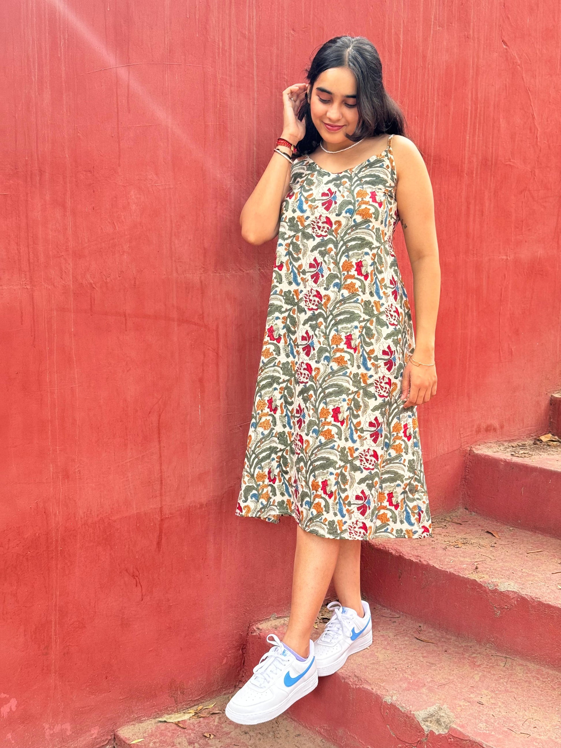 A woman standing on a set of stairs, wearing a floral hand block printed summer dress.