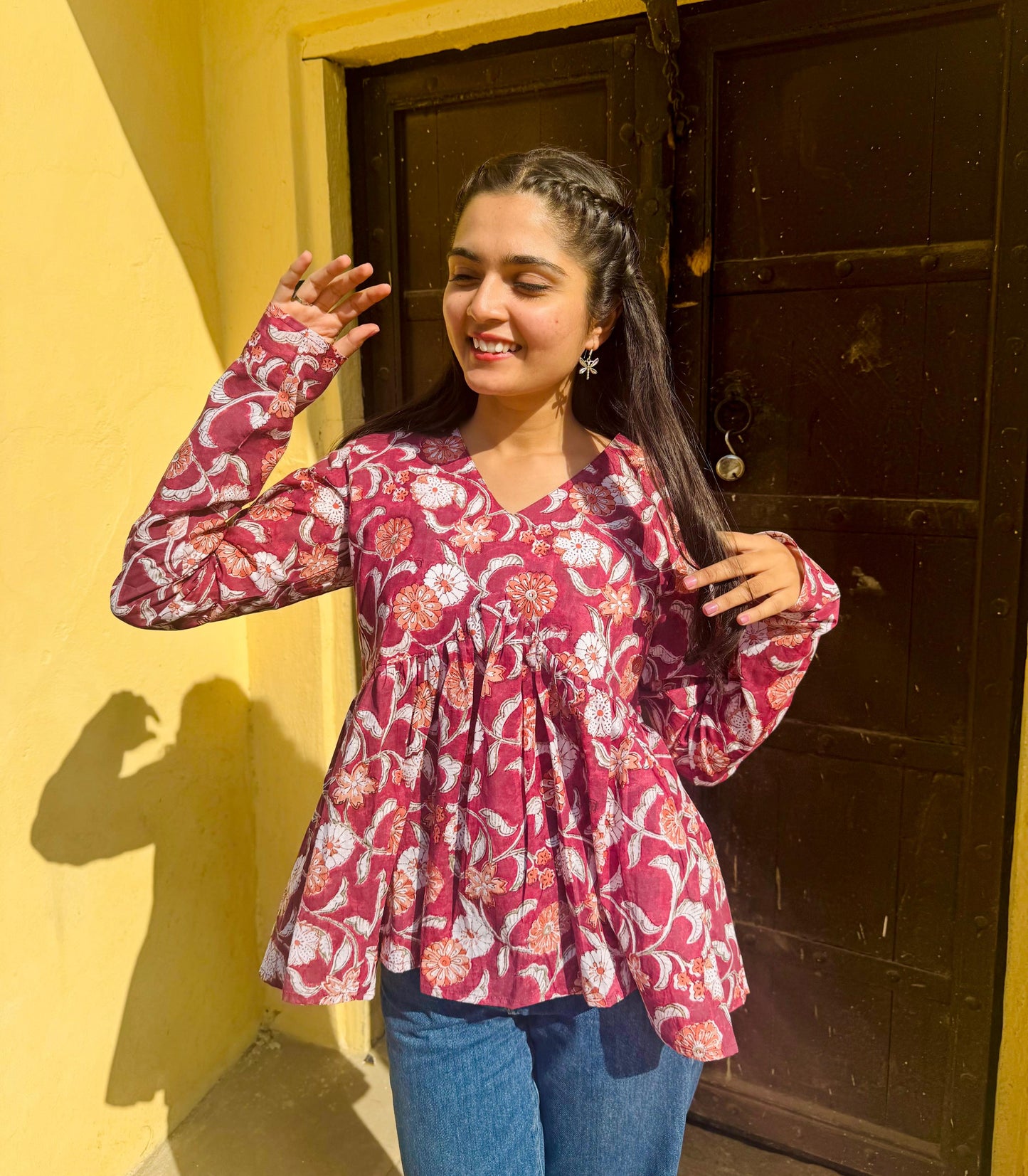 A person wearing a red floral kurta with long sleeves, flared style, and hand-block print design.