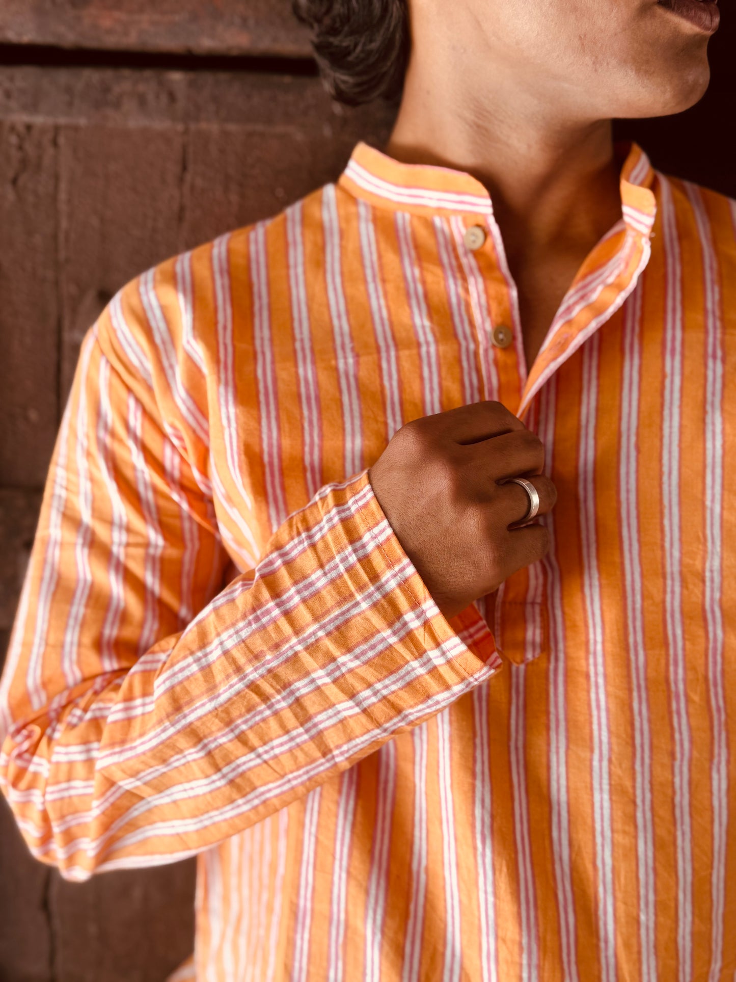 Person wearing an orange and white striped shirt with a blurred background