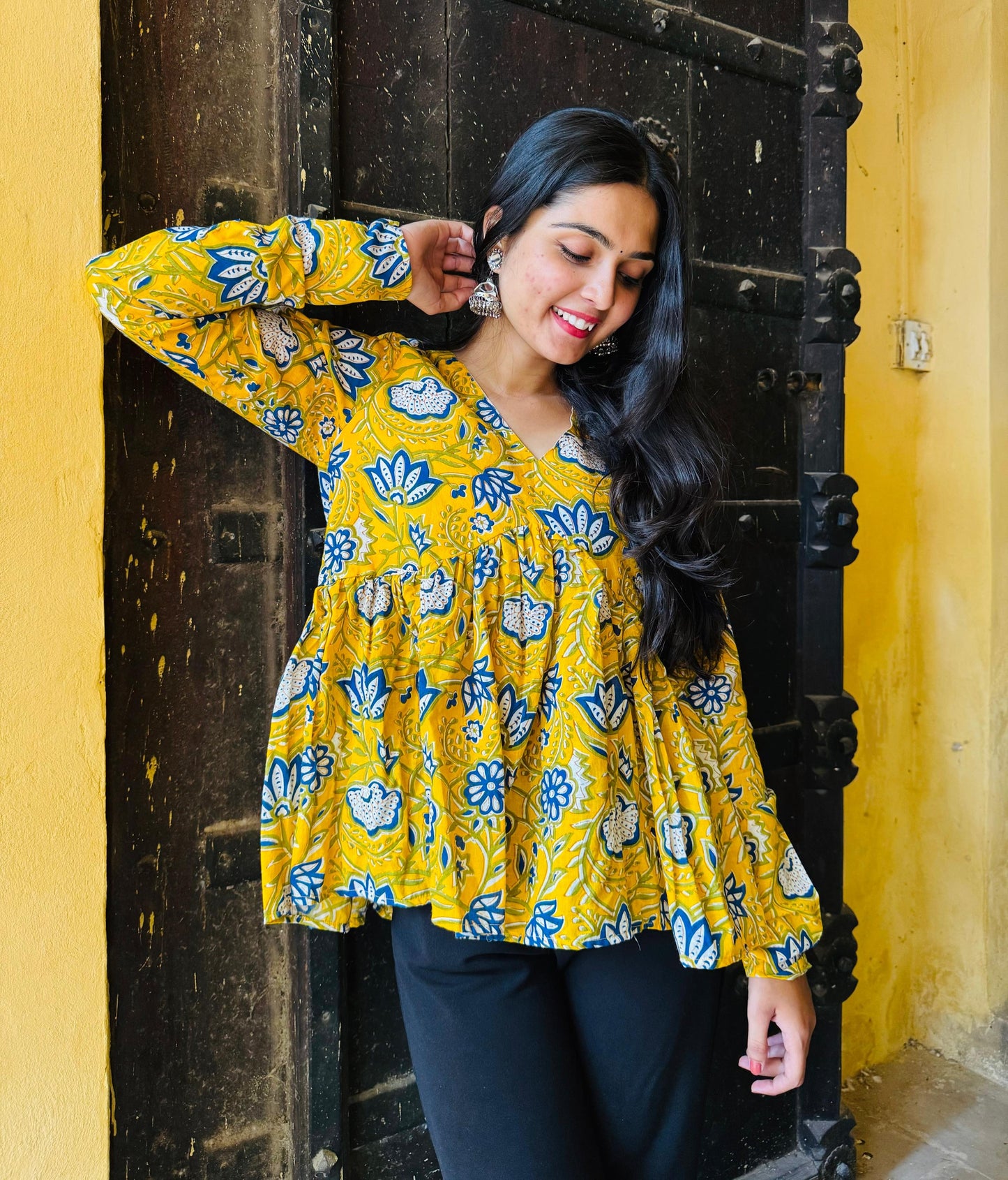 A woman wearing a yellow floral cotton top