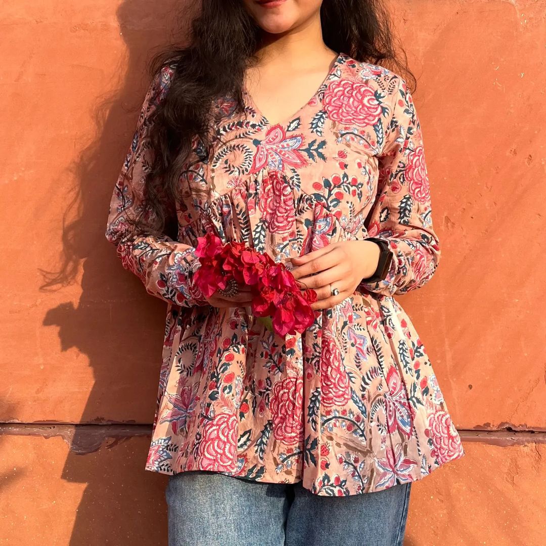 A woman wearing a beige floral cotton top