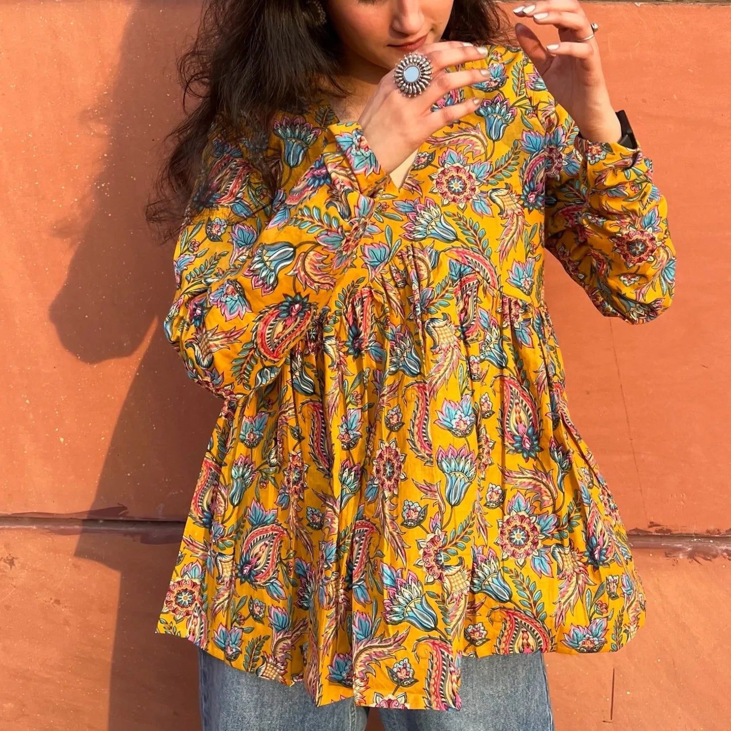 A woman wearing a  floral  yellow cotton top