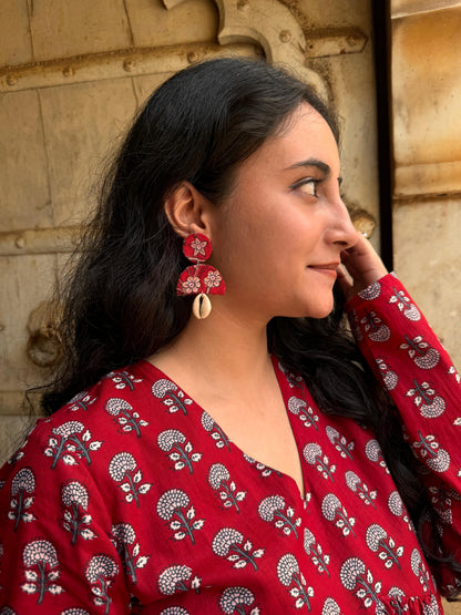 A woman wearing a red floral cotton top  handmade fabric earrings 
