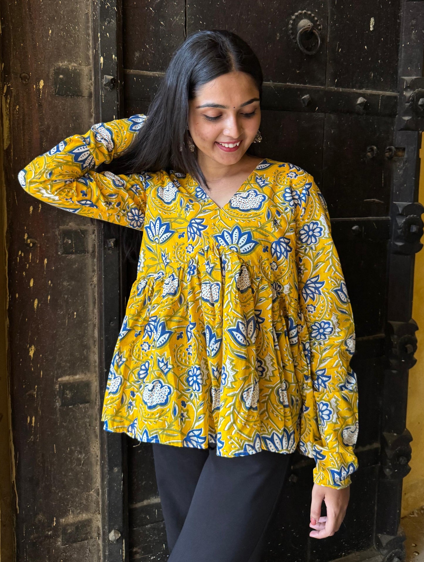 A woman wearing a yellow floral cotton top