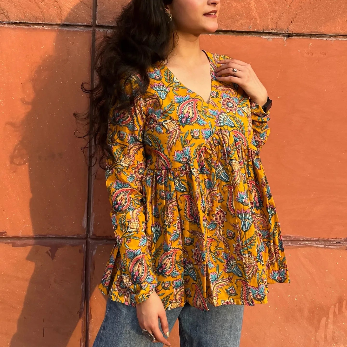 A woman wearing a yellow printed floral cotton top