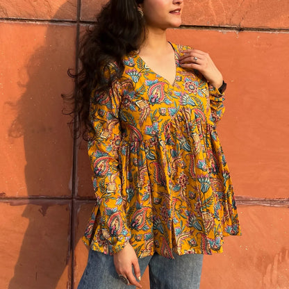 A woman wearing a yellow printed floral cotton top