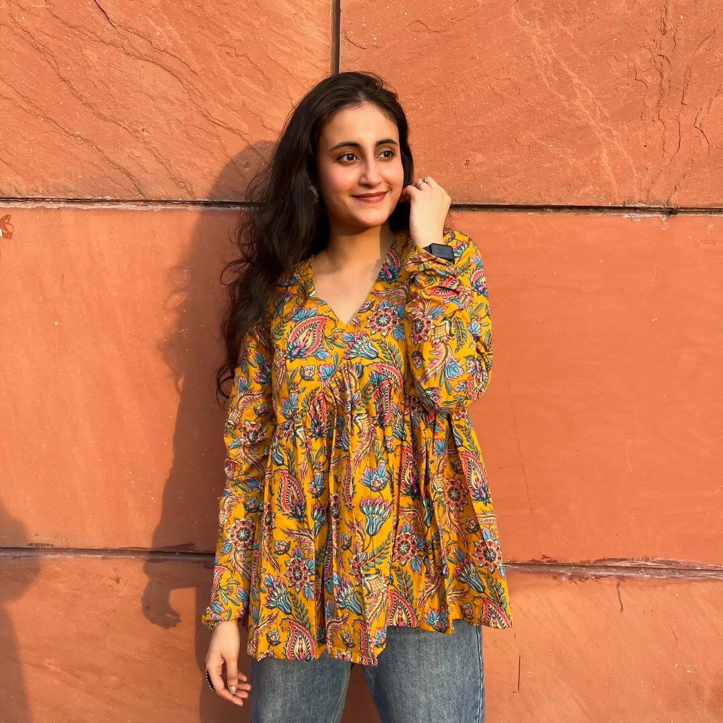 A woman wearing a yellow floral cotton top