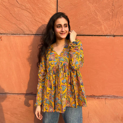 A woman wearing a yellow floral cotton top