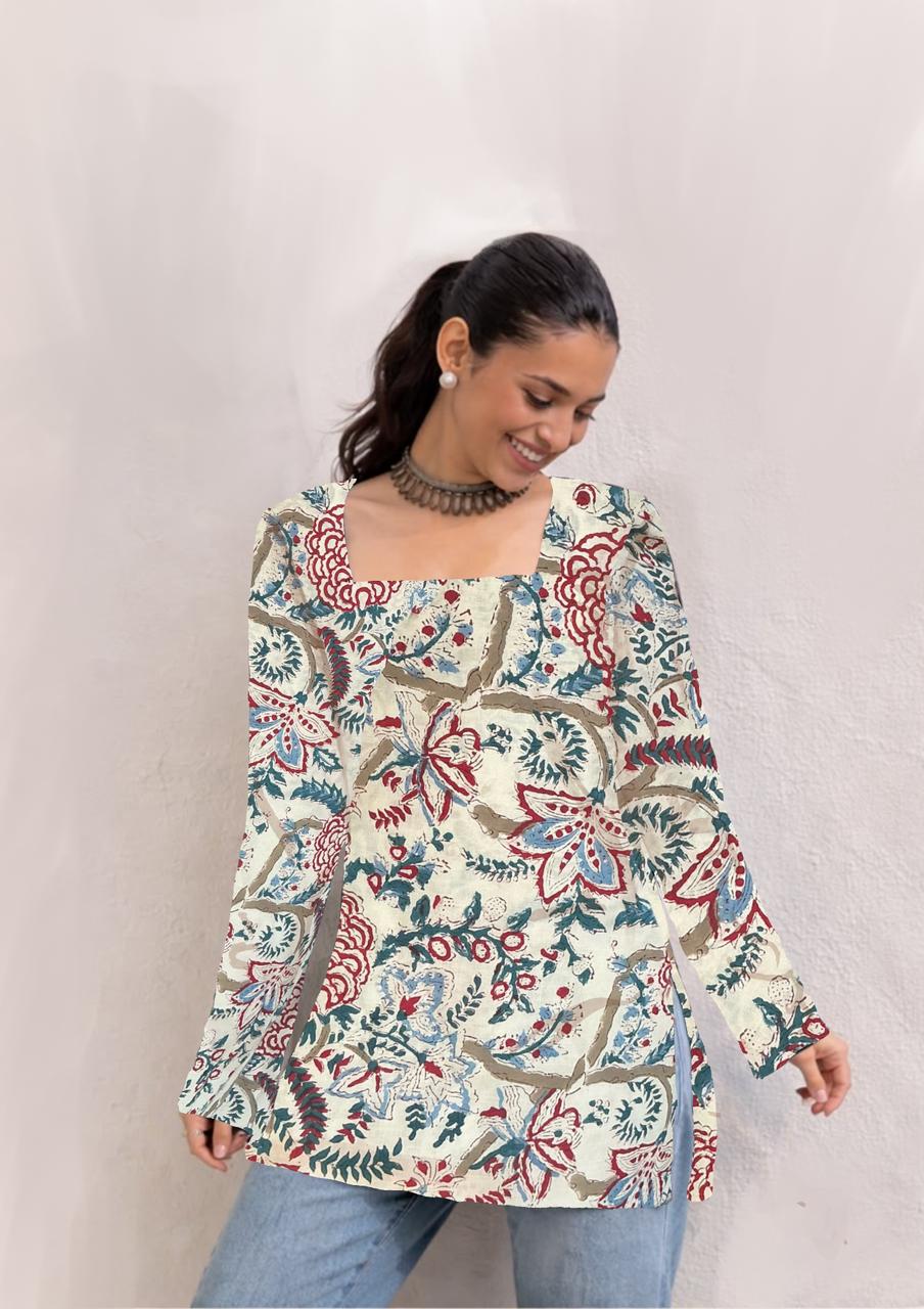 Woman wearing a long-sleeve floral patterned top against a plain background