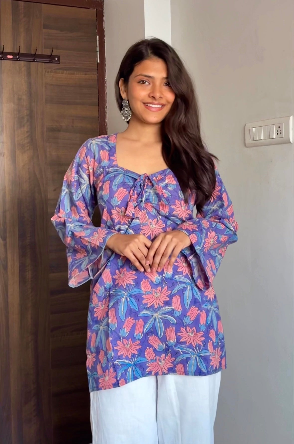 Woman wearing a colorful floral blouse standing indoors.