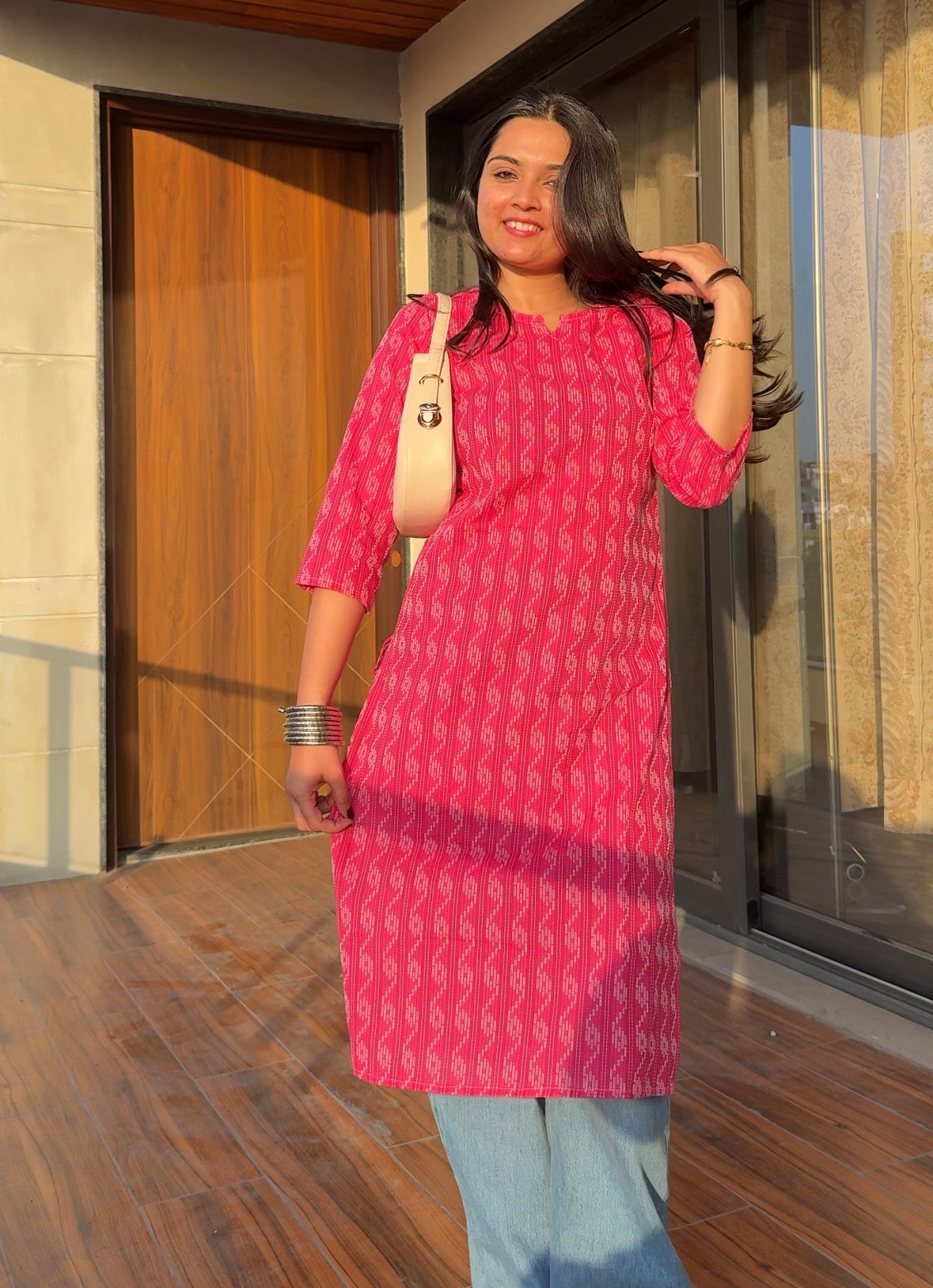 Woman in a pink kurta standing outdoors with a neutral background