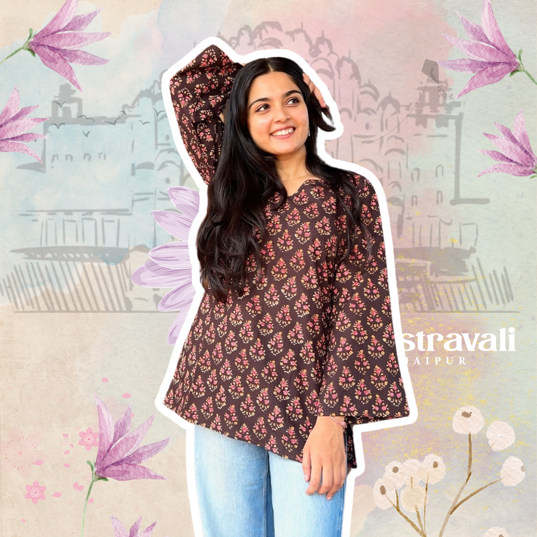 A woman posing in a brown floral printed short kurti with flared sleeves, paired with blue jeans.