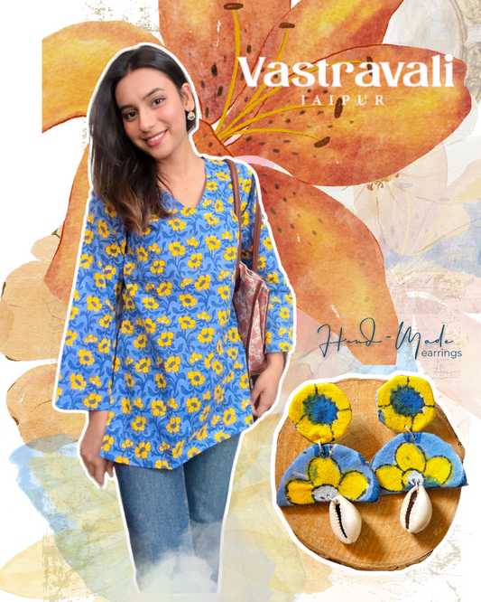 Woman wearing a blue floral top with earrings on a decorative background featuring the brand 'Vastravali'.