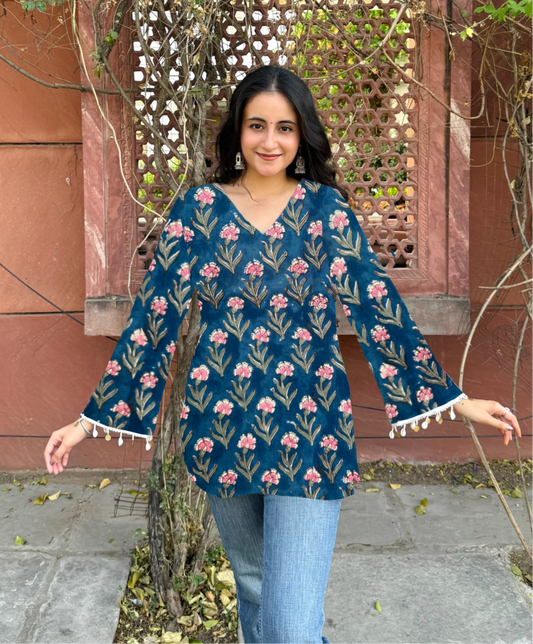 Woman wearing a blue floral blouse with tassels in an outdoor setting