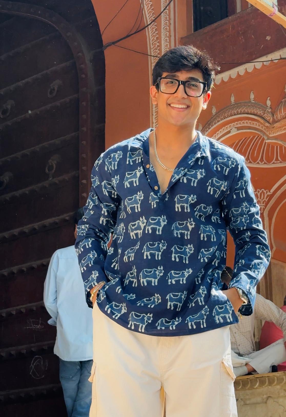 Person wearing a blue patterned shirt with a decorative background