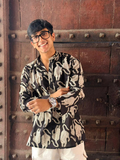 Person wearing a patterned shirt standing in front of a textured wall.