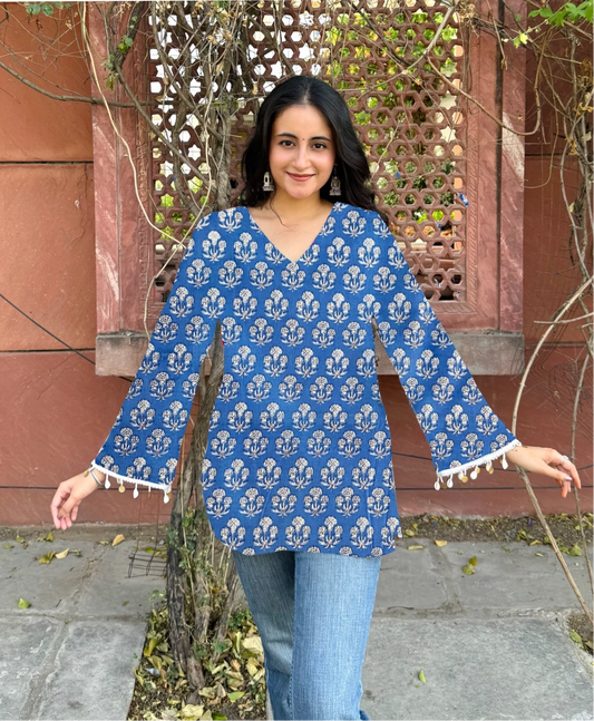 Woman wearing a blue floral blouse with white patterns and trim, standing outdoors.