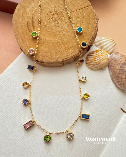 Gold necklace with colorful gemstones on a wooden block with seashells