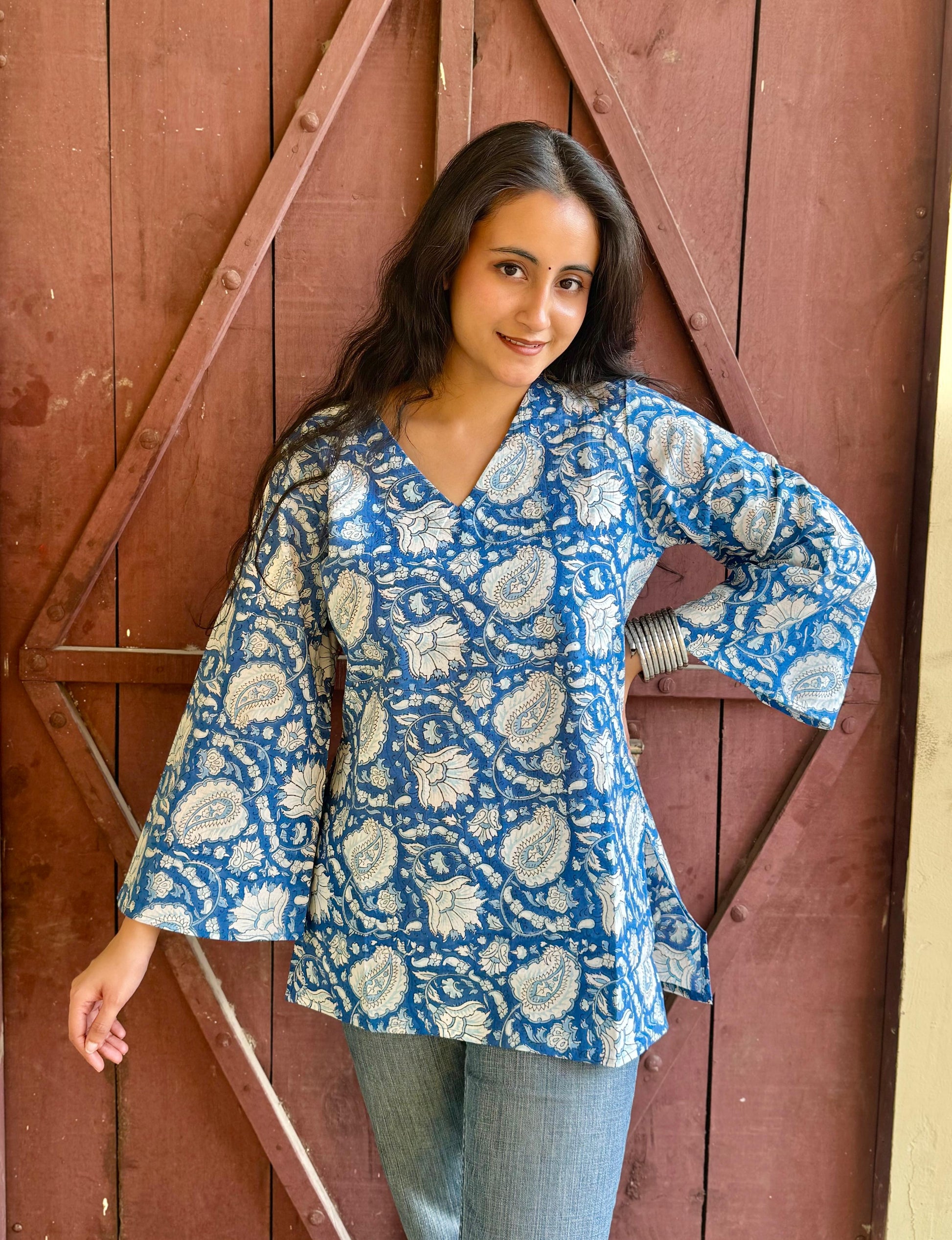 A woman wearing a blue and white hand-block printed short kurti with flared sleeves.