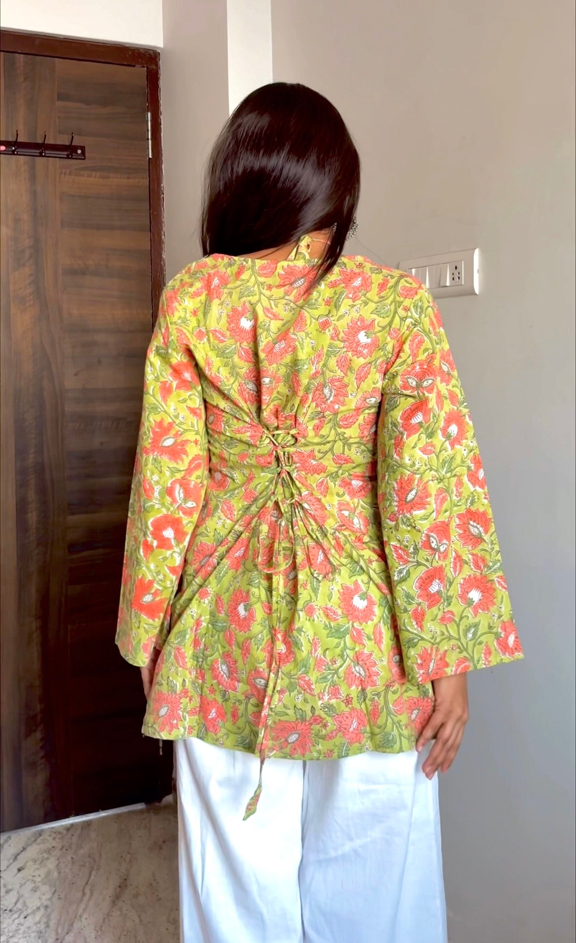 Person wearing a green floral jacket indoors.