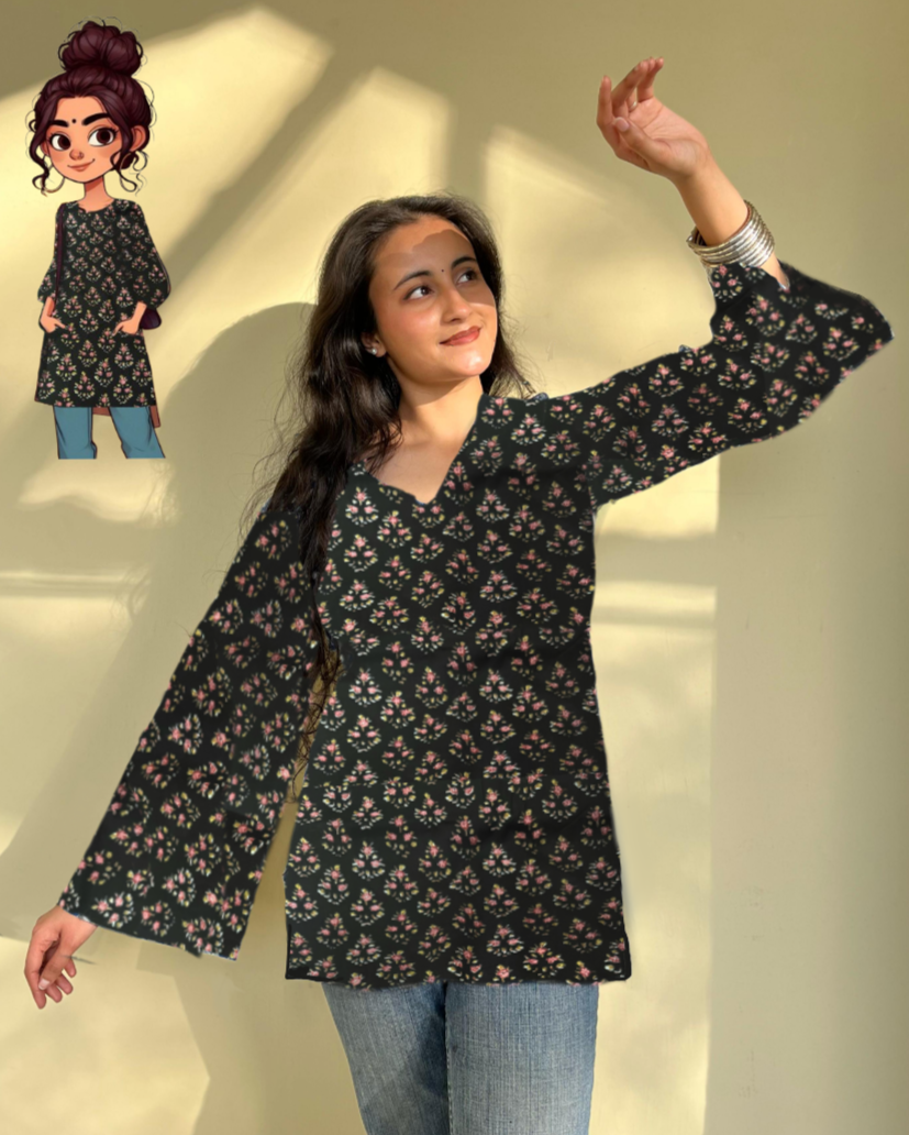 A woman wearing a floral printed black short kurti with flared sleeves, paired with blue jeans. There is also a small illustration of a woman's face in the corner, possibly representing the designer or brand.